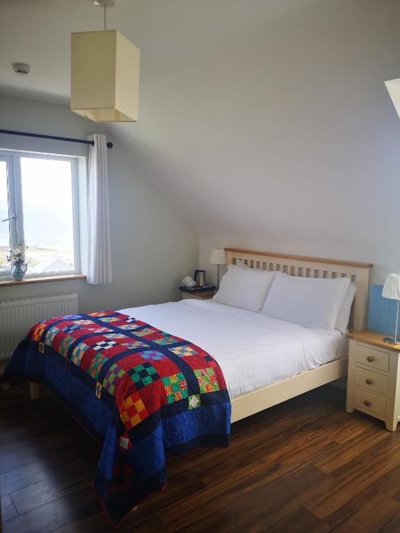 a bedroom with a bed with a colorful blanket on it at An Creagán Rooms in Inisheer