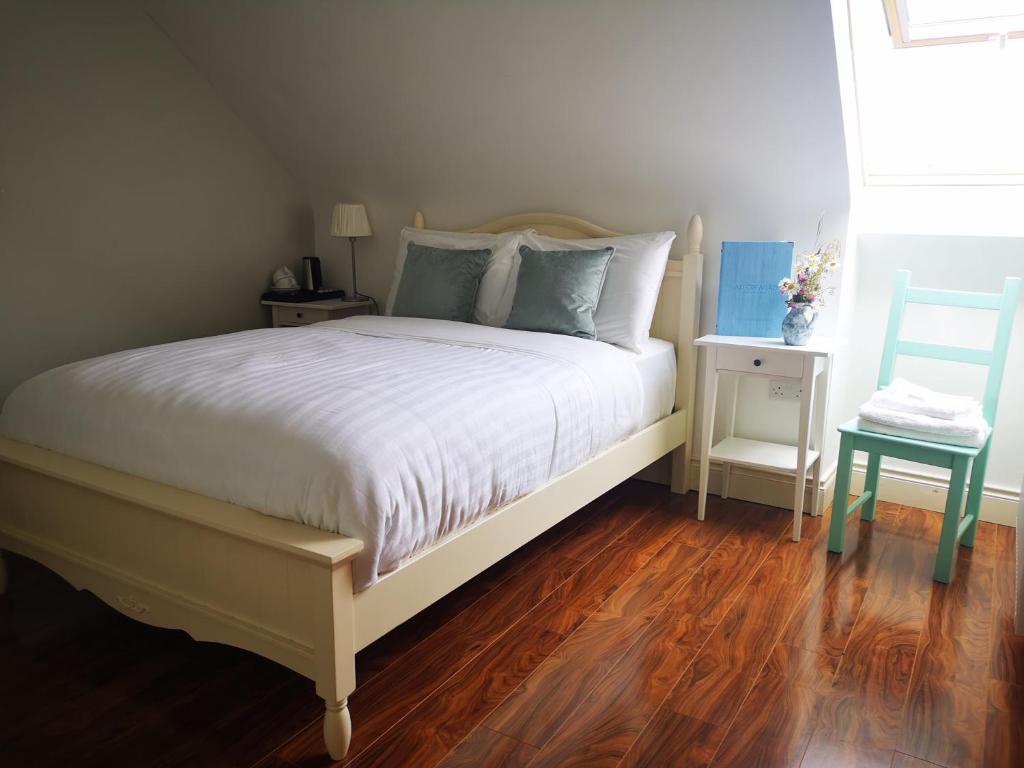 a bedroom with a white bed with a wooden floor at An Creagán Rooms in Inisheer