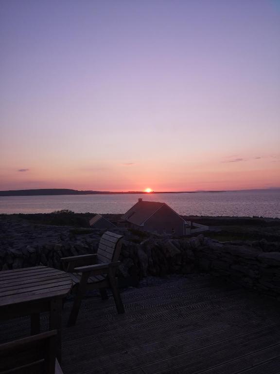 a sunset over the water with a tent and a bench at An Creagán Rooms in Inisheer