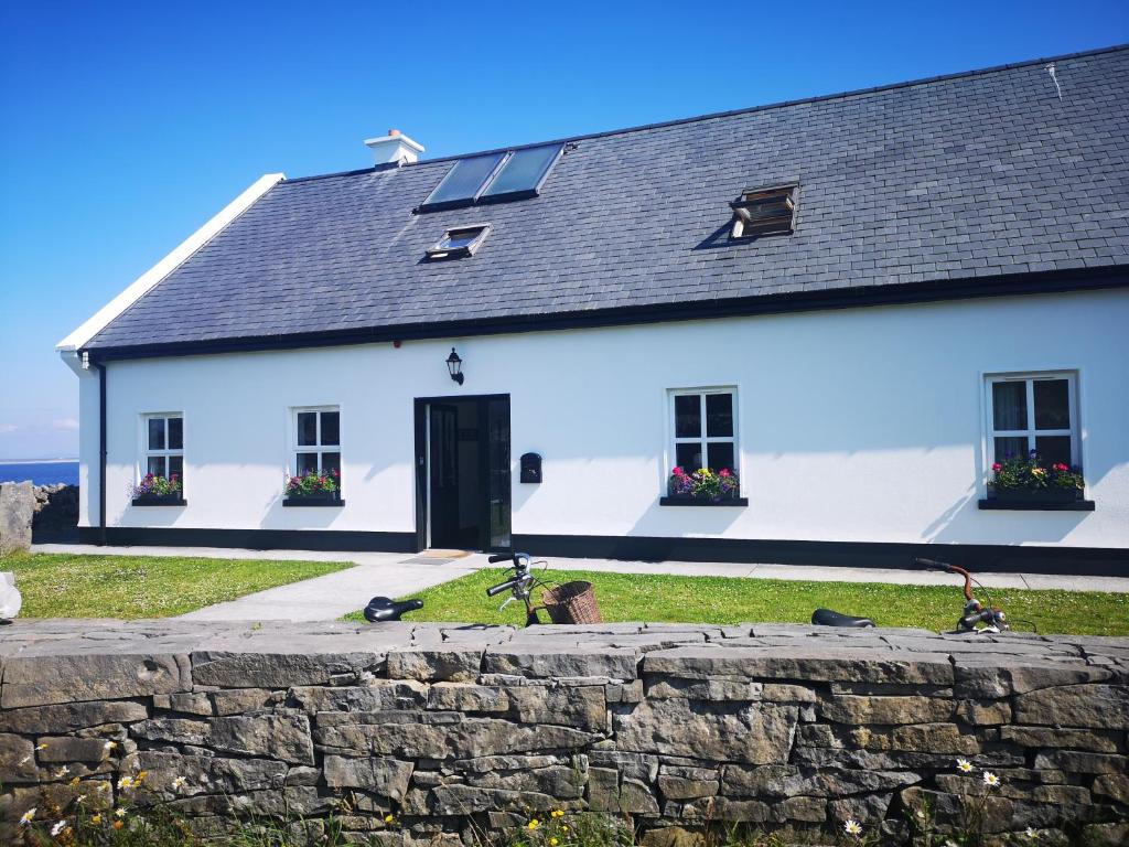 a white house with a stone wall in front of it at An Creagán Rooms in Inisheer