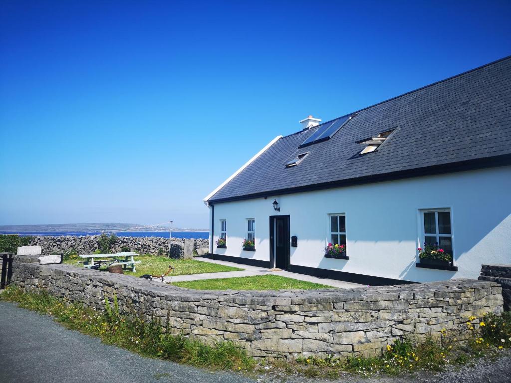 a white house with a stone wall next to a building at An Creagán Rooms in Inisheer