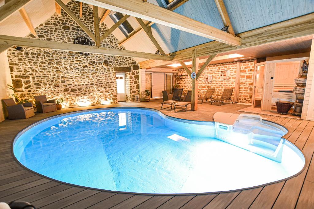 una gran piscina en una habitación con una pared de piedra en La Brocherie, en Magny-le-Désert