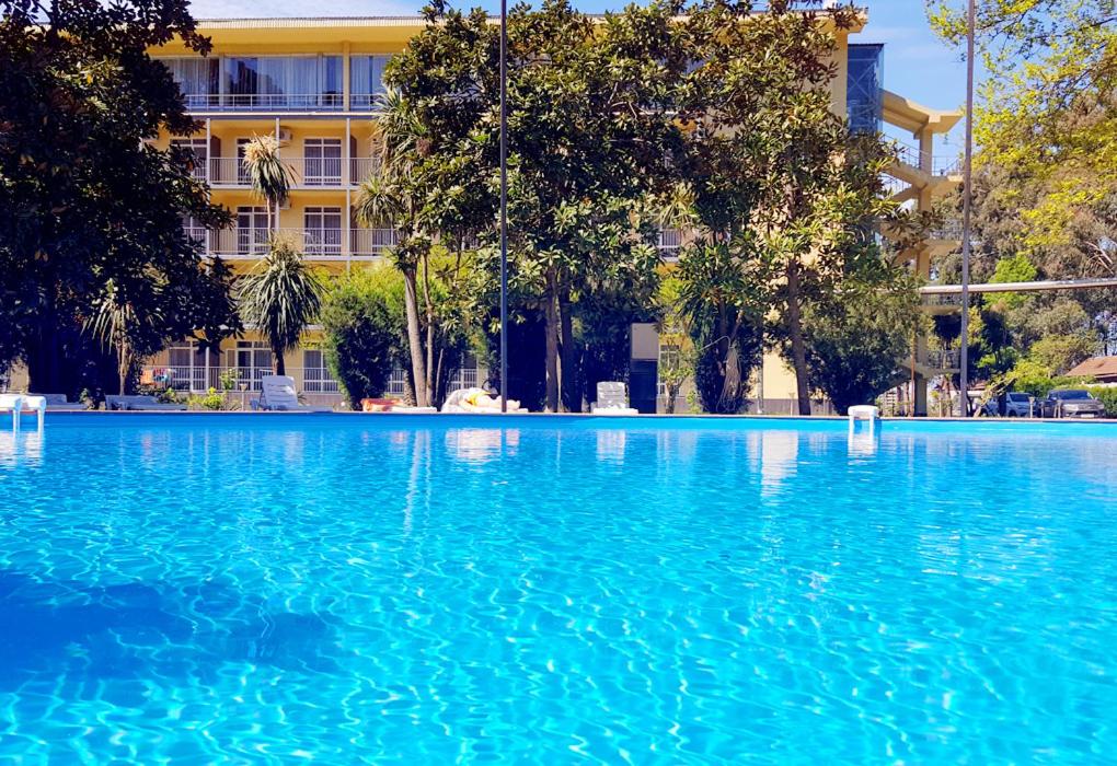 una grande piscina di acqua blu di fronte a un edificio di Wellness Park Hotel Gagra All-Inclusive a Gagra