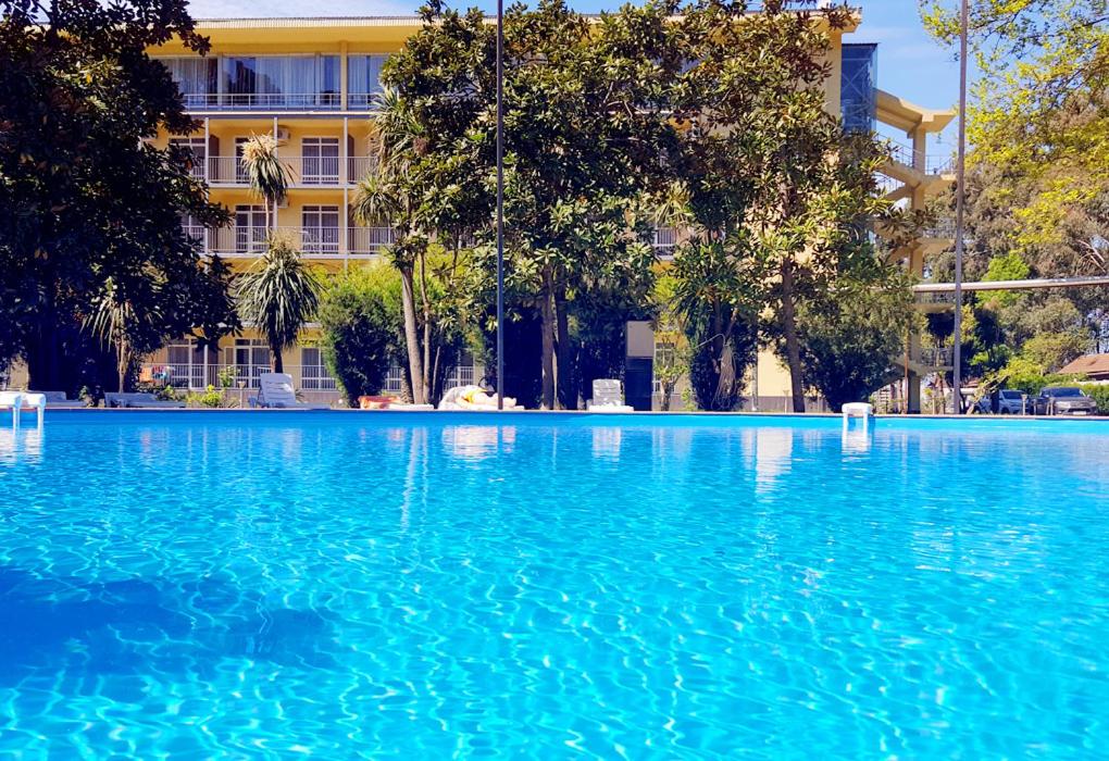 a large pool of blue water in front of a building at Wellness Park Hotel Gagra All-Inclusive in Gagra