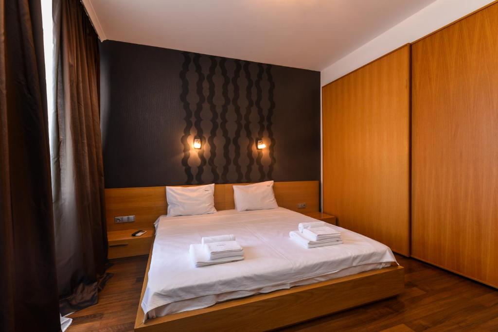 - une chambre avec un lit doté de draps blancs et de placards en bois dans l'établissement Super Premium Two Bedroom Suite on Vitosha Boulevard, à Sofia