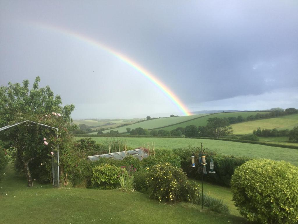 een regenboog in de lucht boven een tuin bij North Hollacombe Farm in Crediton