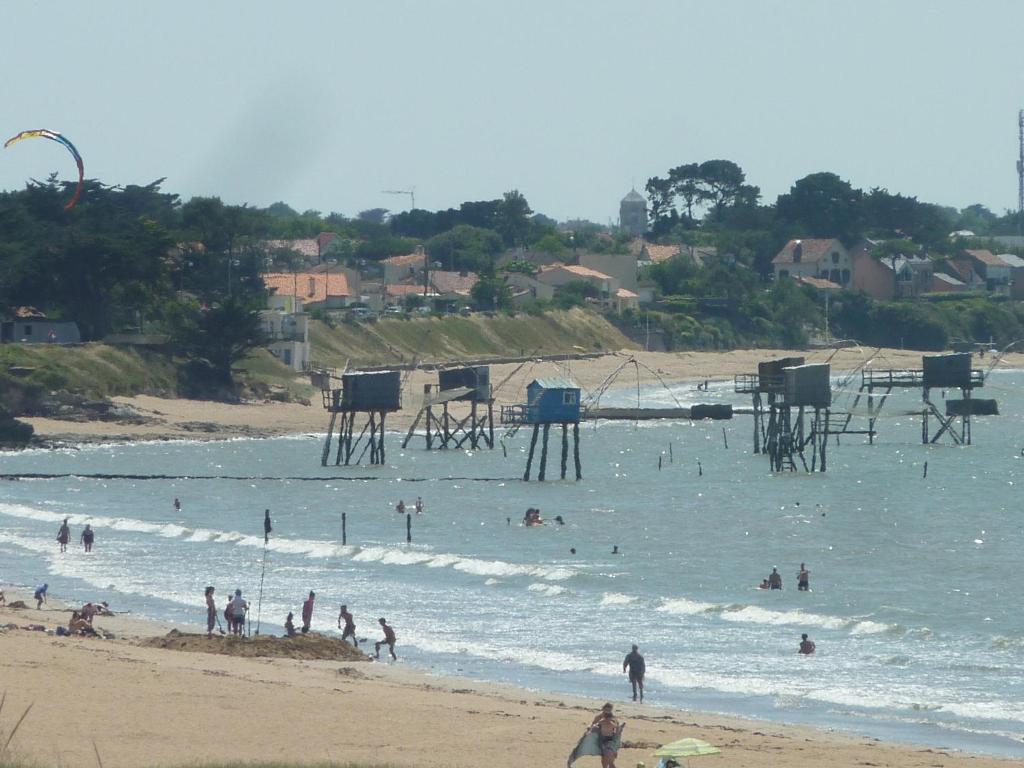 un groupe de personnes dans l'eau sur une plage dans l'établissement Chambre d'Hôtes La Dune - face mer, à Saint-Michel-Chef-Chef