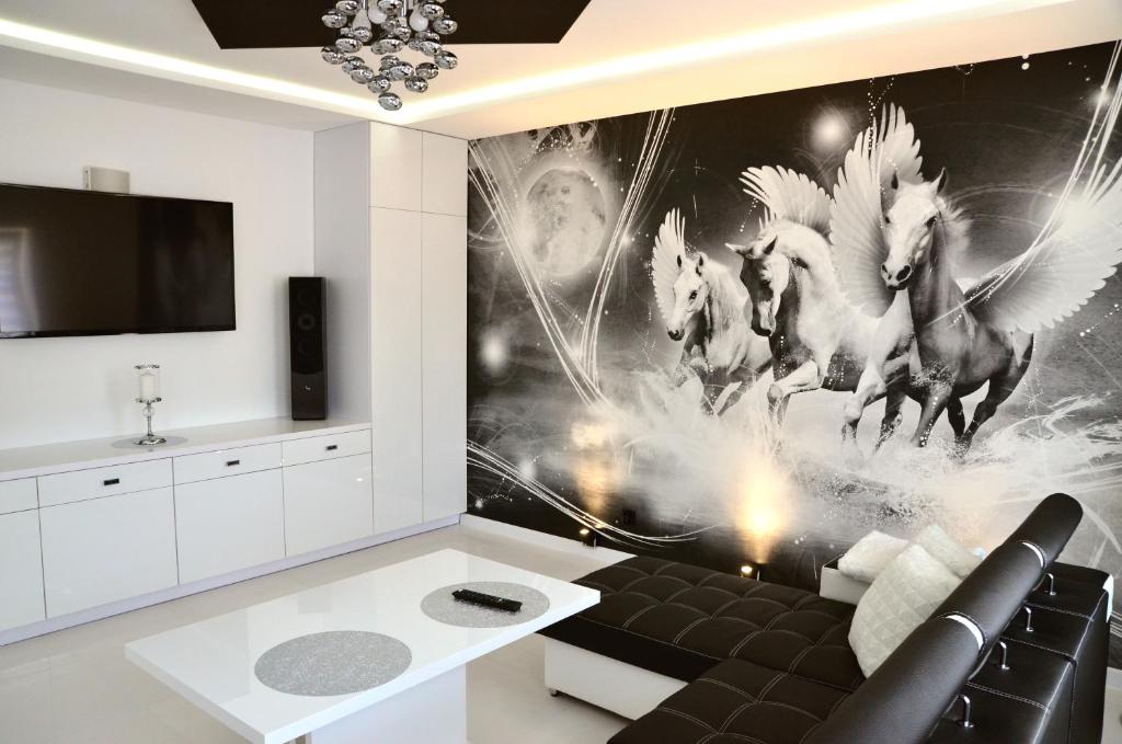 sala de estar con sofá y mural de caballos en la pared en Apartament Pegaz, en Gniezno