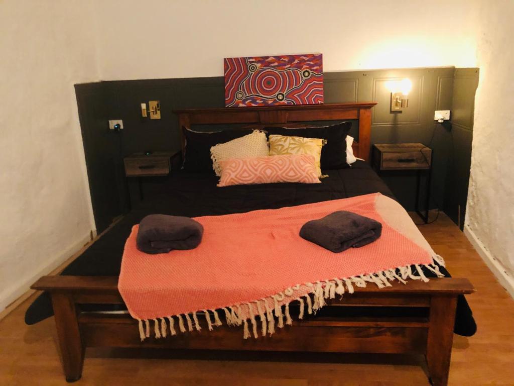 a bedroom with a large bed with two towels on it at The Blacklighters Opal Retreat-Undergound in Coober Pedy