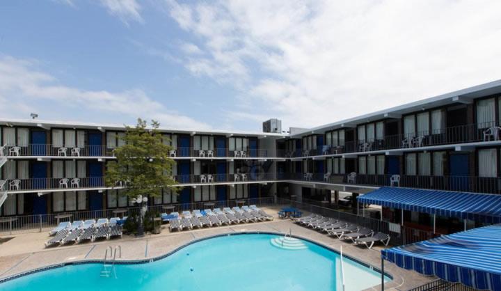 a large hotel with a swimming pool and chairs at Brittany Motel in Wildwood