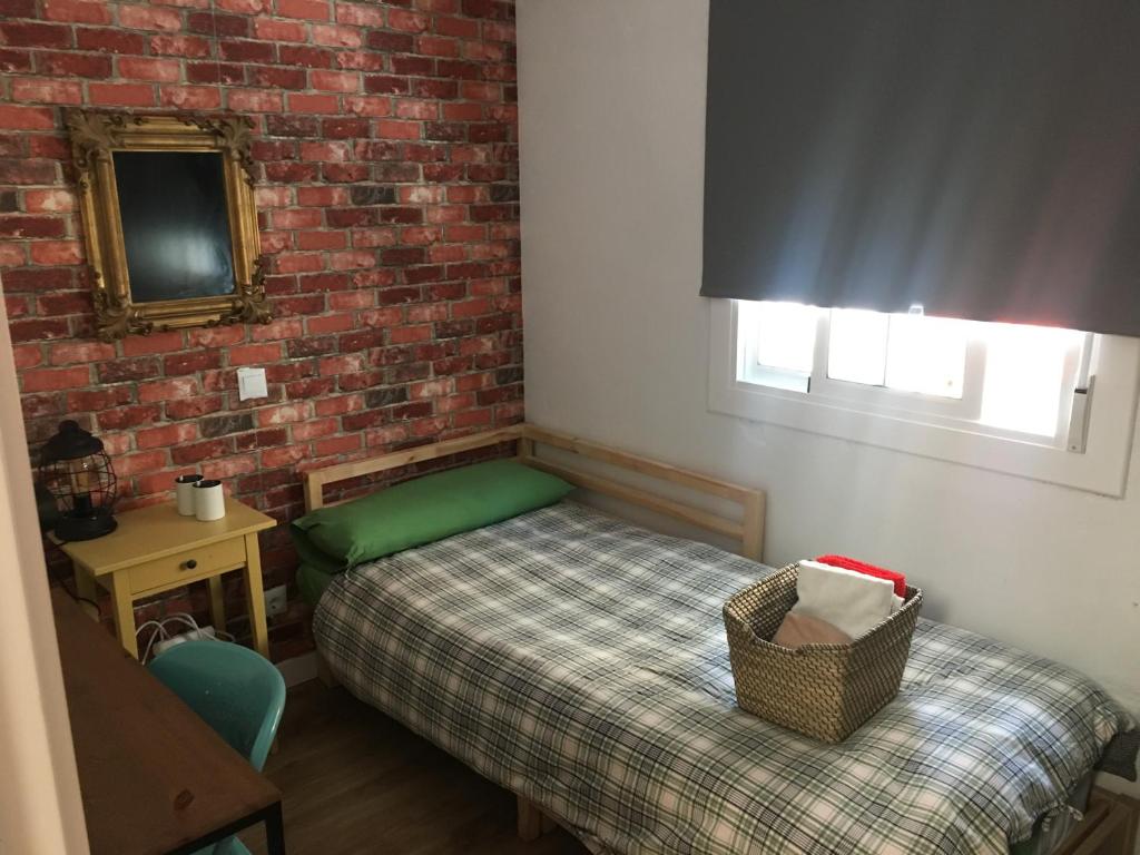 Dormitorio pequeño con cama y pared de ladrillo en Practical room: Barcelona-Fira-Airport, en Hospitalet de Llobregat