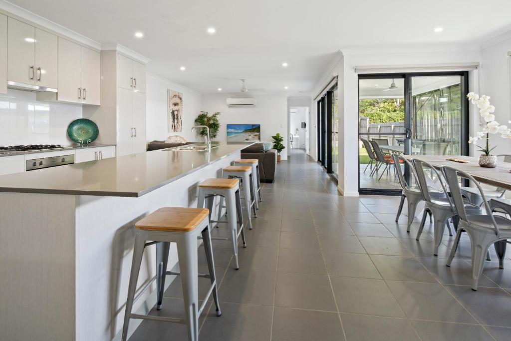 a kitchen with white cabinets and bar stools at Whitsundays Paradise by the Port in Airlie Beach