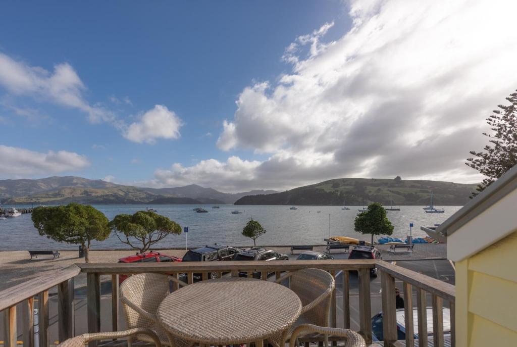 a balcony with chairs and a view of a lake at Akaroa Waterfront Apartment in Akaroa