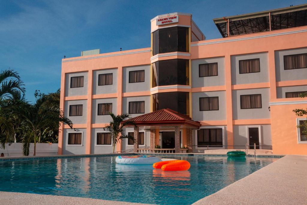 a hotel with a swimming pool in front of a building at Adams View Hotel in Moalboal