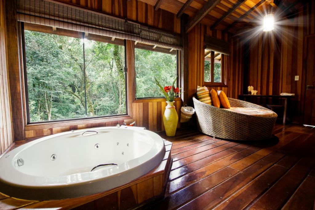 a large bathroom with a large tub and a window at Pousada Ahavanoah in Monte Verde