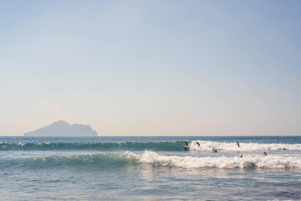 a group of people riding waves in the ocean at Ocean Sky Homestay in Toucheng