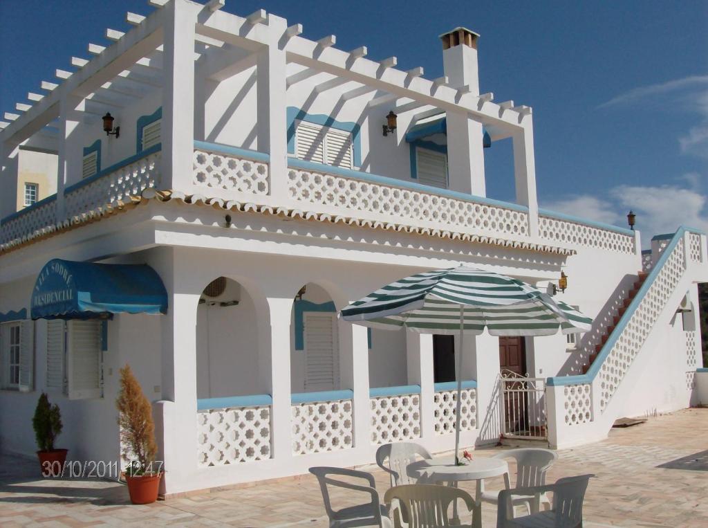 een wit huis met een tafel en een paraplu bij Vila Sodré Guest House in Silves