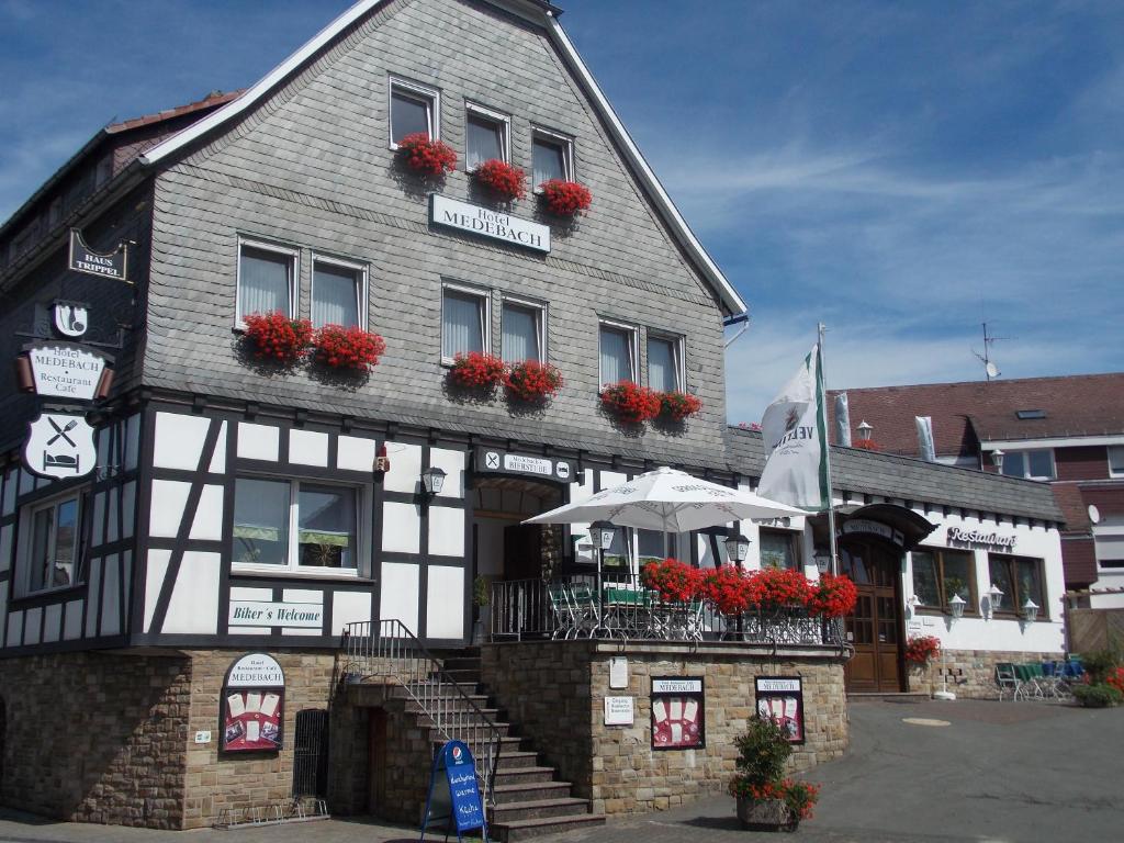 a black and white building with flowers in the windows at Hotel Medebach - Zum Schwanenkönig in Medebach