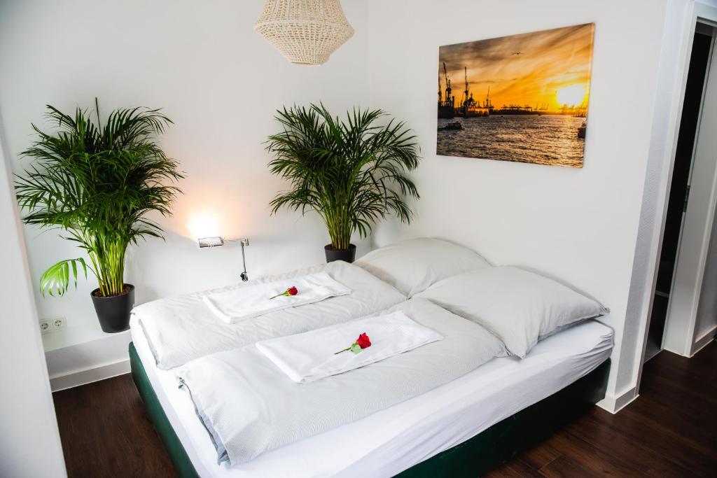 a bed with two white pillows and plants in a room at St Pauli CITY Apartment in Hamburg