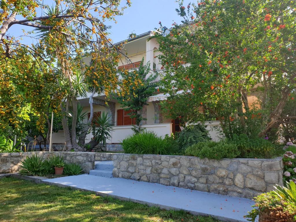 a house with a stone retaining wall and trees at Apartments Davorka in Rab