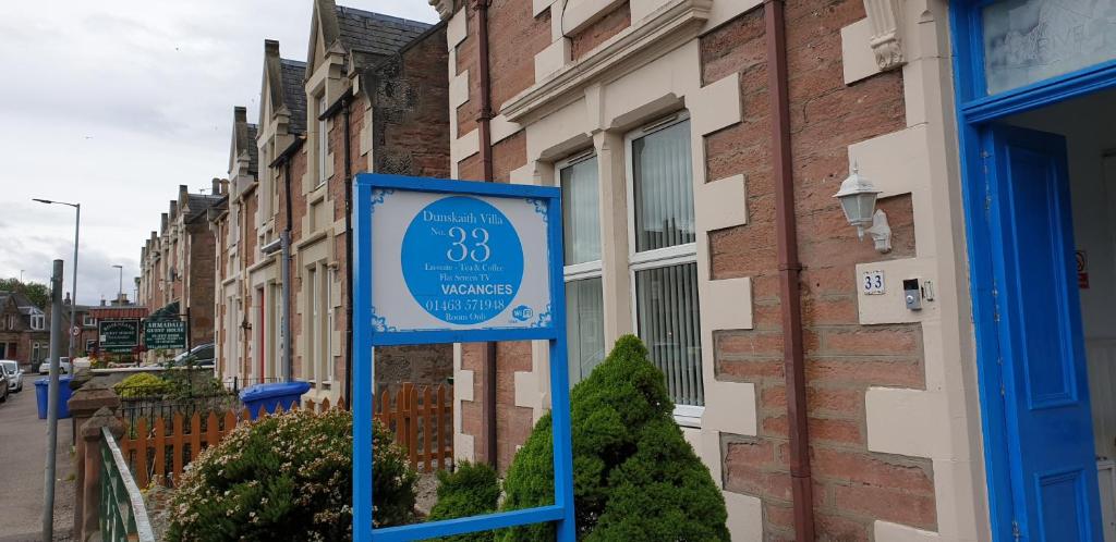 una señal azul frente a un edificio en Dunskaith Villa, en Inverness