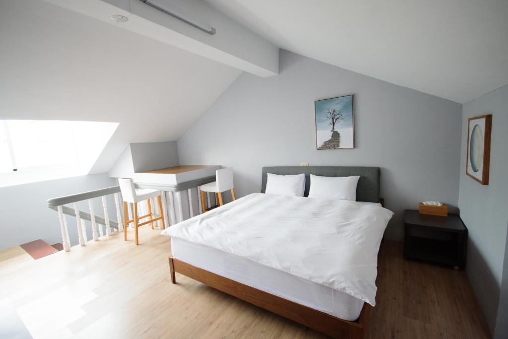 a bedroom with a white bed and a staircase at Green 58 B&amp;B in Hengchun South Gate