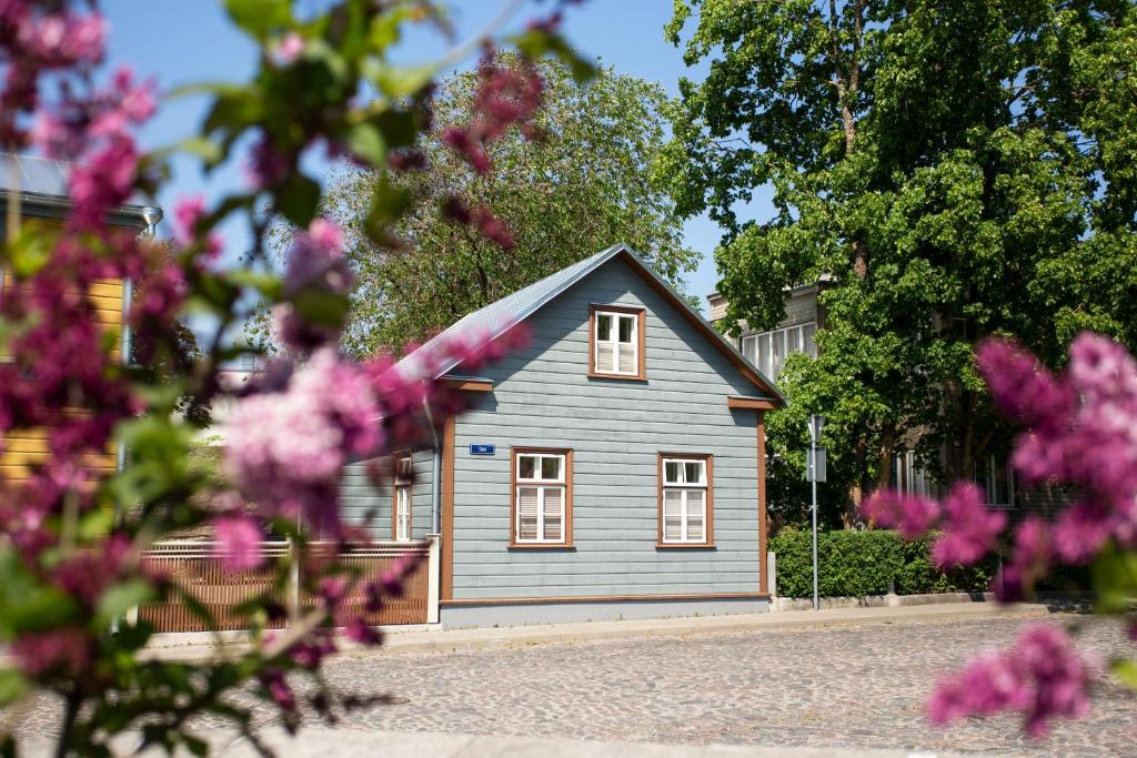 a small blue house with white windows and pink flowers at Silbernagel Apartment in Kuressaare