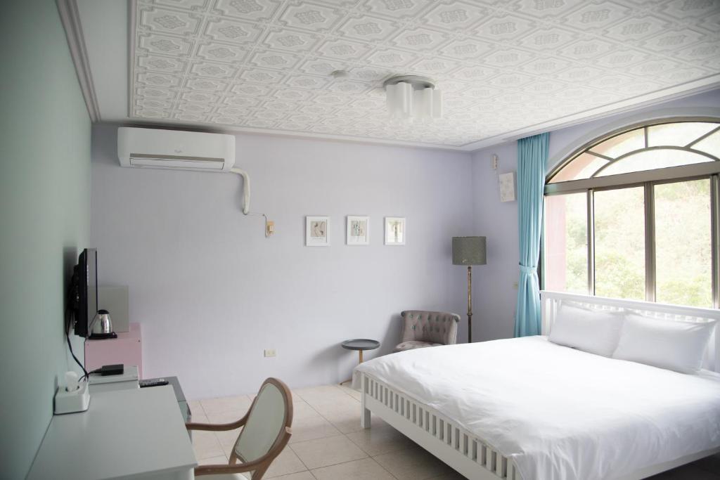 a bedroom with a white bed and a window at Green 58 B&amp;B in Hengchun South Gate
