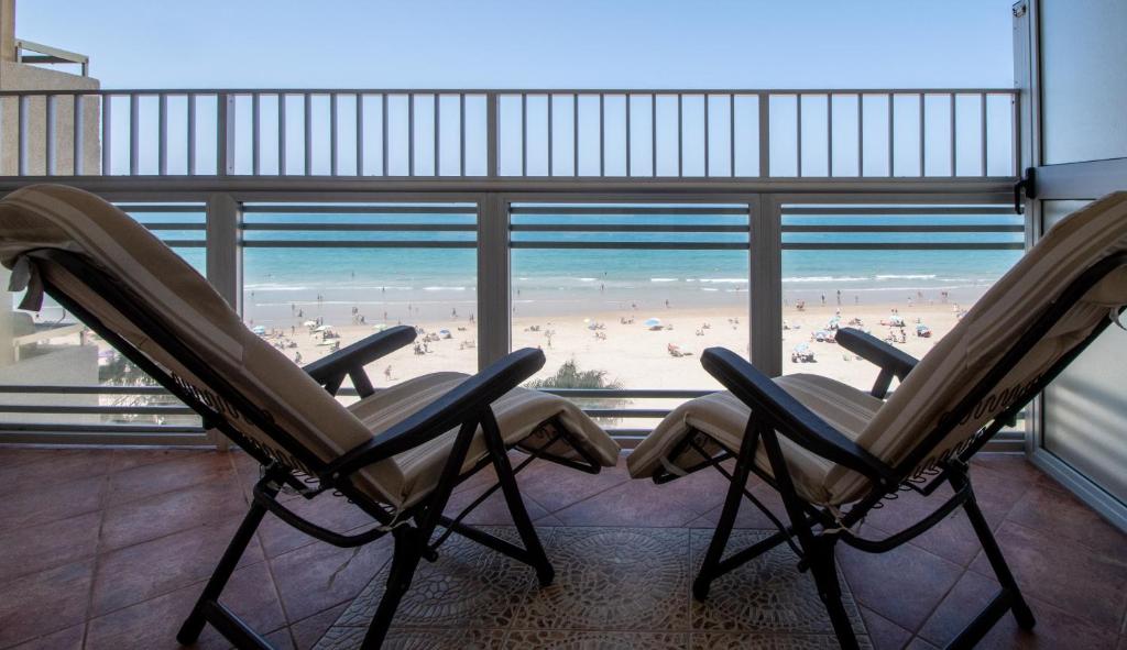 two chairs in a room with a view of a beach at Apartamento Paseo Maritimo 27 in Cádiz