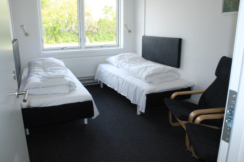 a room with two beds and a chair and a window at Motel Poppelvej in Herning