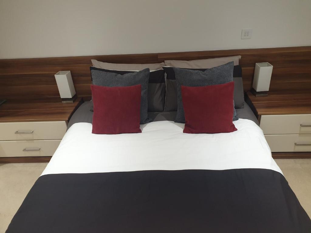 a bed with red and grey pillows on it at Hullidays - The Sawmill Suite in Hull