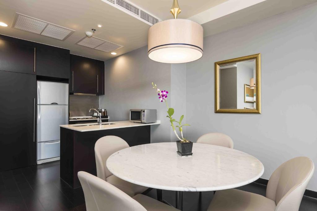 a kitchen and dining room with a white table and chairs at Chatrium Hotel Riverside Bangkok in Bangkok