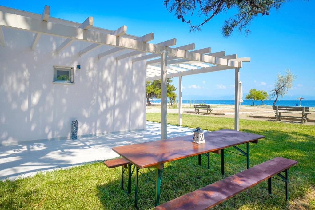 a picnic table under a pergola next to the beach at Studios Periklis in Prinos
