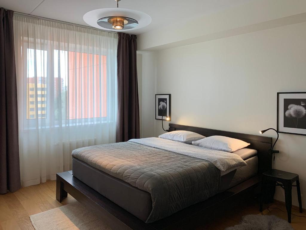 a bedroom with a bed and a large window at Orange Sipelga Balcony & Free Parking in Tallinn