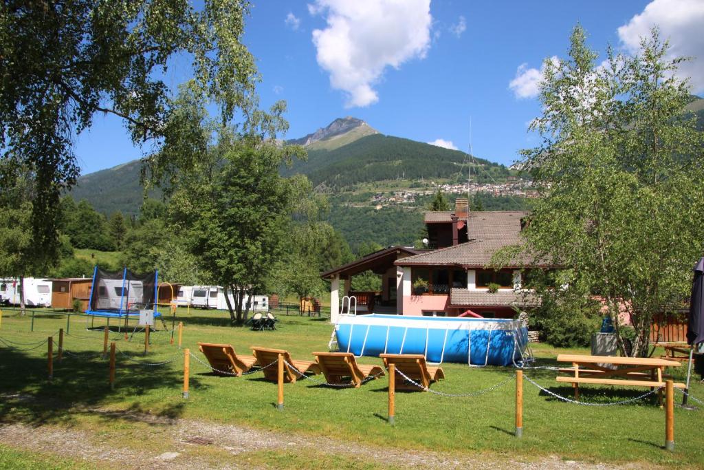 a group of chairs sitting in a field with a house at Chalet Presanella in Temù