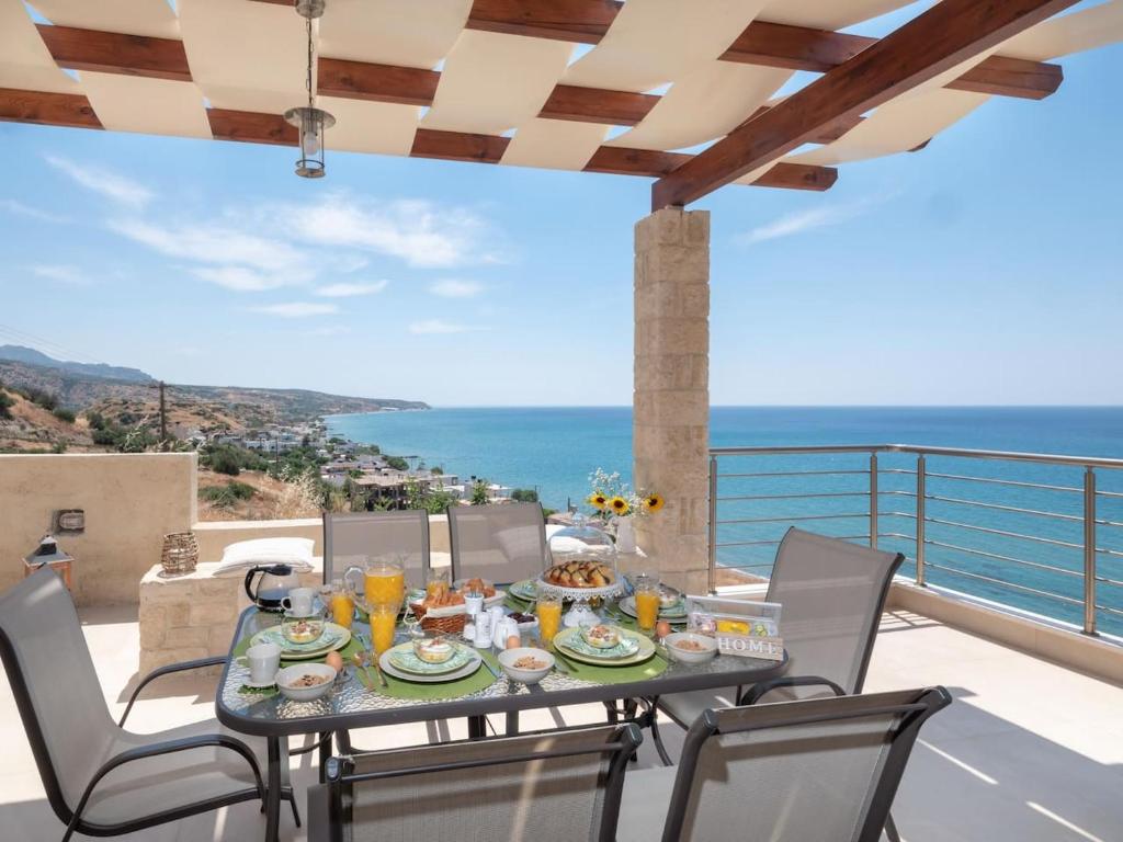a table and chairs on a balcony with a view of the ocean at Private Luxury 3bdrm Villa - Walk to beach in Keratokampos