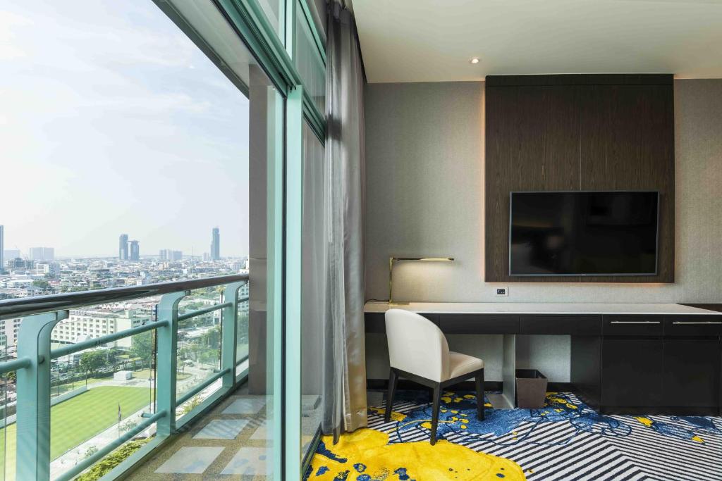 a room with a desk and a view of a city at Chatrium Hotel Riverside Bangkok in Bangkok