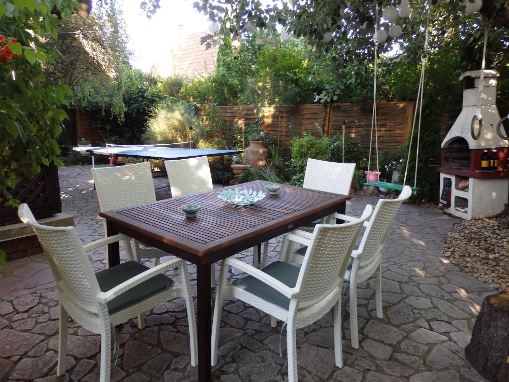 - une table en bois avec des chaises blanches et un grill dans l'établissement Orgona Vendégház, à Velence