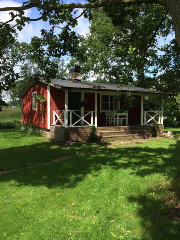 uma casa vermelha com um alpendre e um jardim de relva em Tråvad Nybo Lilla huset em Tråvad