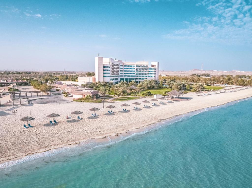 uma vista aérea de uma praia com cadeiras e guarda-sóis em Danat Jebel Dhanna Resort em Jebel Dhanna