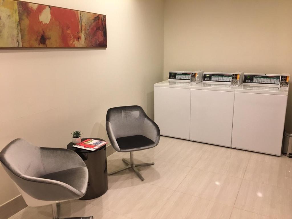 a waiting room with two chairs and washing machines at Fullon Hotel Taoyuan Airport Access MRT A8 in Guishan
