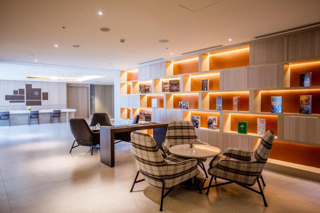 a lobby with chairs and a table and shelves at Fullon Hotel Taoyuan Airport Access MRT A8 in Guishan