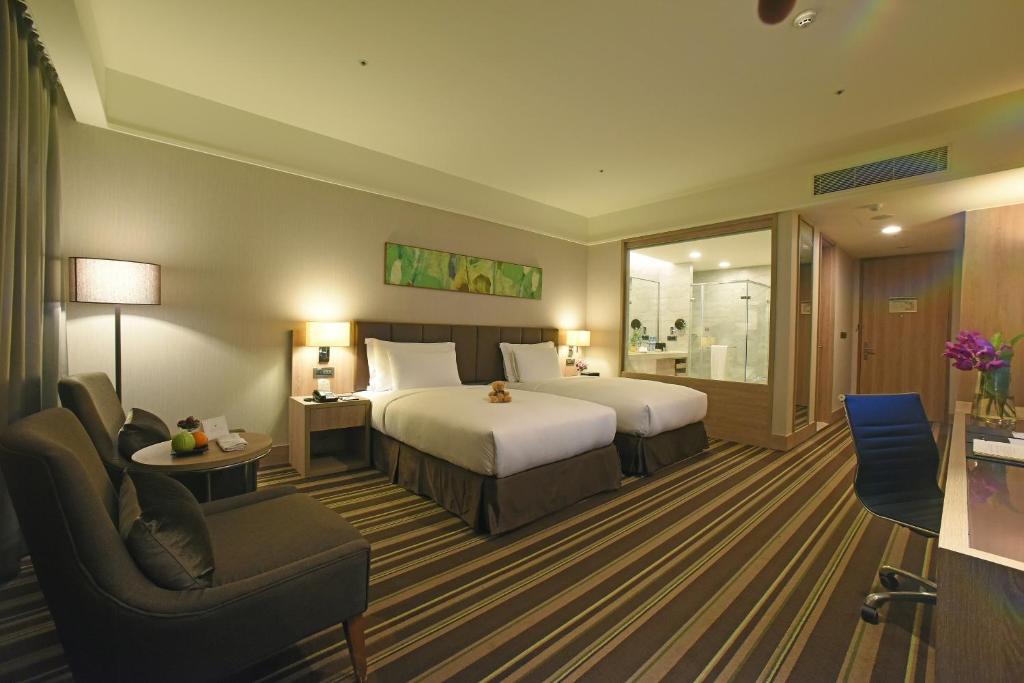 a hotel room with two beds and a chair at Fullon Hotel Taoyuan Airport Access MRT A8 in Guishan