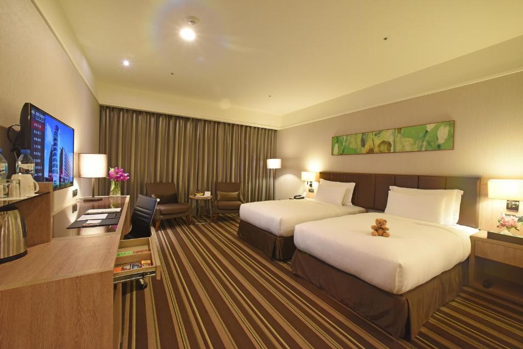 a hotel room with two beds and a flat screen tv at Fullon Hotel Taoyuan Airport Access MRT A8 in Guishan