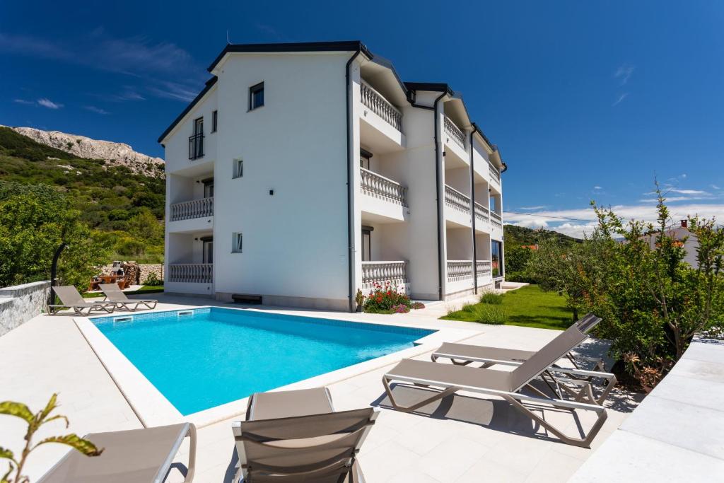 
a large white house sitting in front of a pool at Bed & Breakfast Došen in Baška
