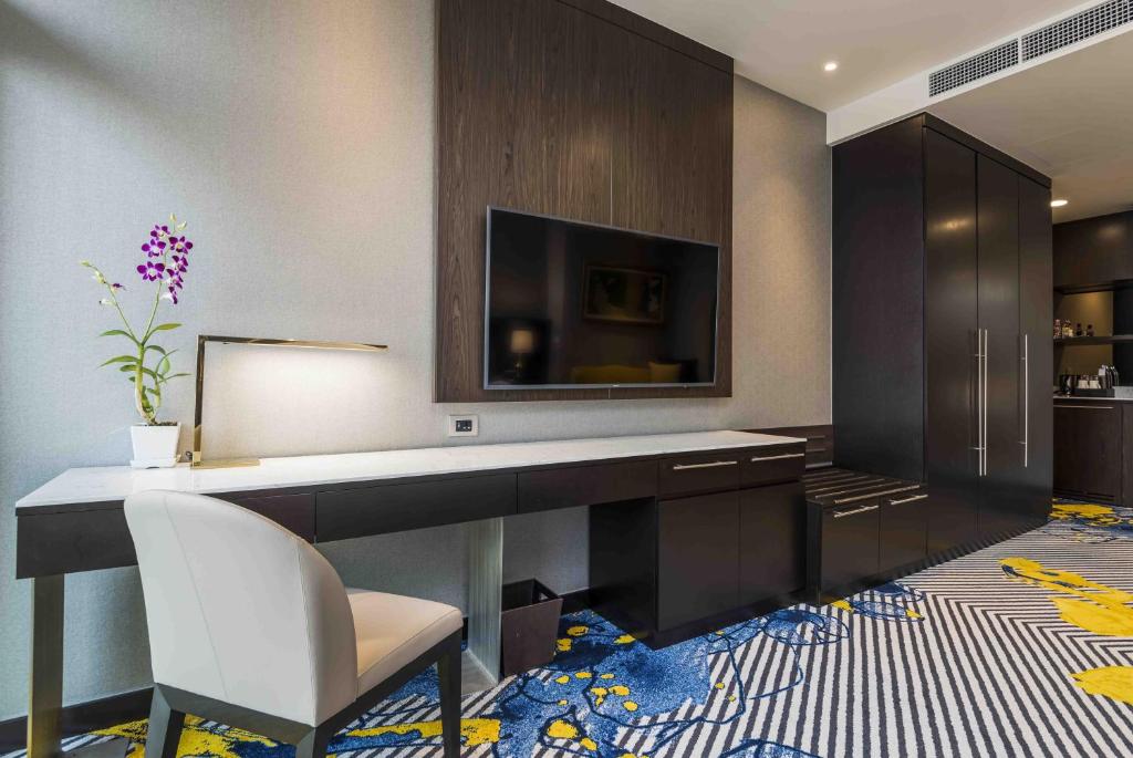 A built-in desk and chair sit beside a wall-mounted television and a dark storage cabinet.