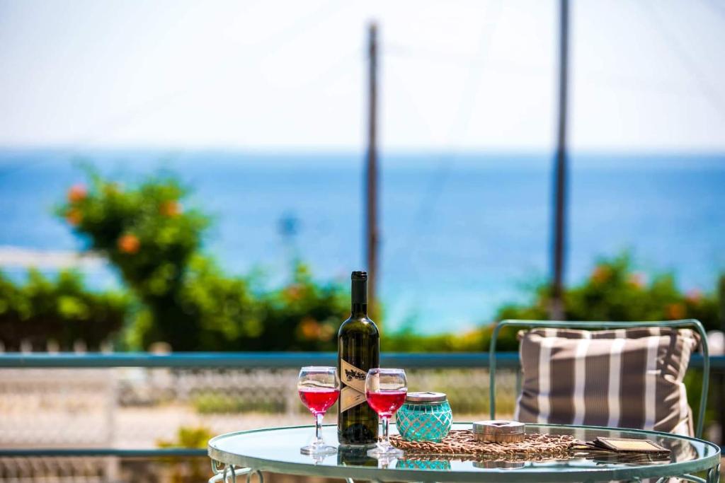 Sweet Home Glikadi في لايميناس: طاولة مع كأسين من النبيذ وزجاجة من النبيذ