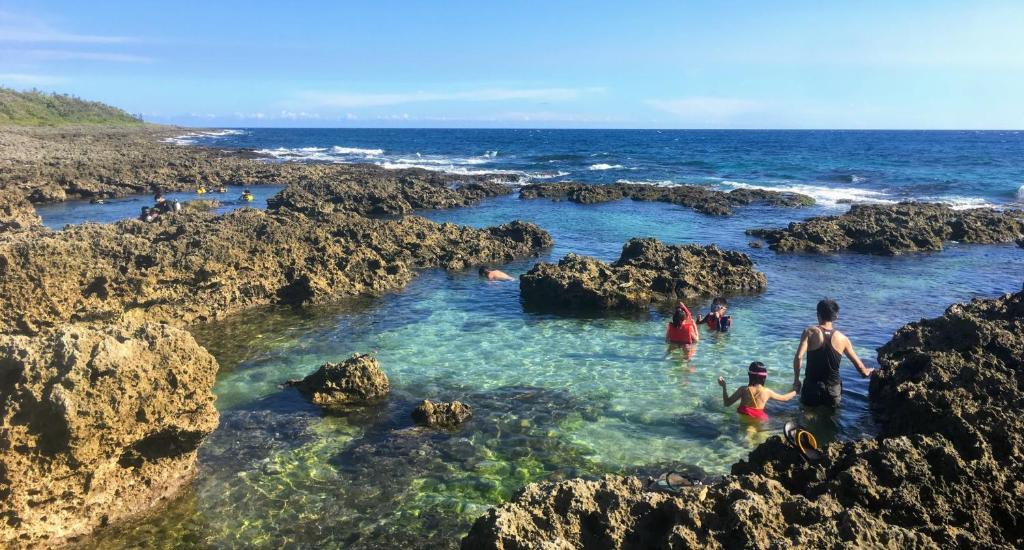 a group of people standing in the water in rocks at 灣境海邊小屋 in Eluan