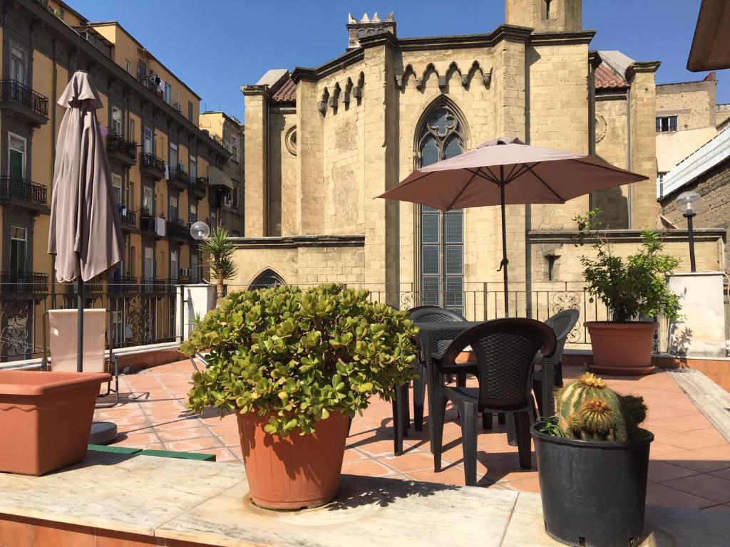 un patio con mesa, sillas y sombrilla en B&B La Storia Di Napoli, en Nápoles