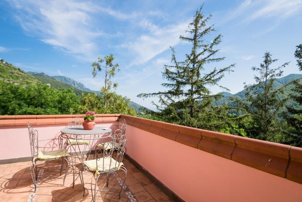 a balcony with two chairs and a table and a tree at Belvedere di Gloria in Tramonti